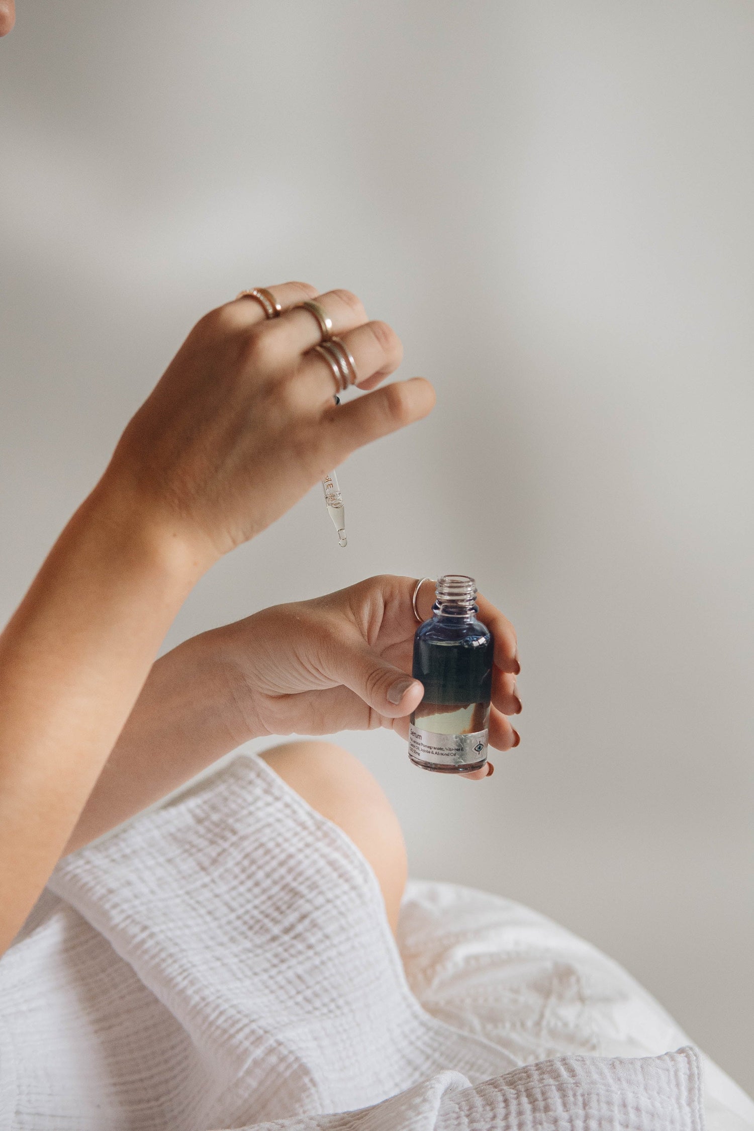 Person dispensing skincare serum onto their hand using a pipette